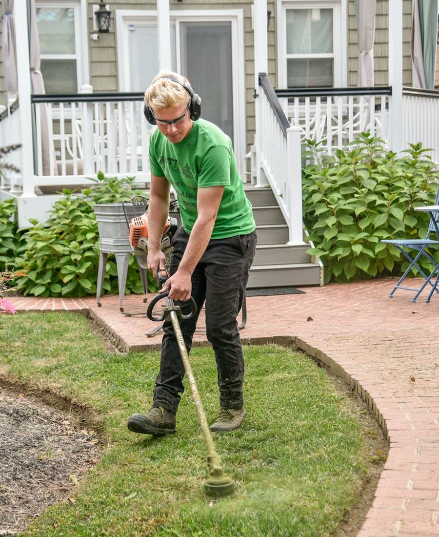 Owner trimming along a front walk in a green crew shirt